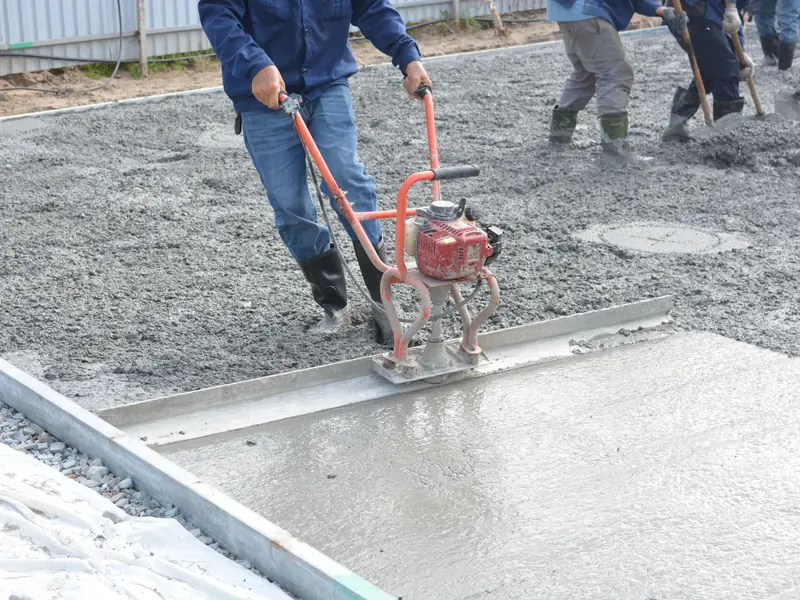 Fresh concrete being leveled with a power screed