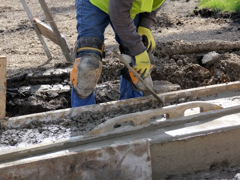 Hand trowel smoothing fresh concrete at a form edge